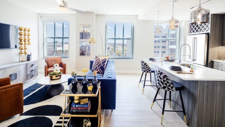 a living room with a blue couch and a white table at The First
