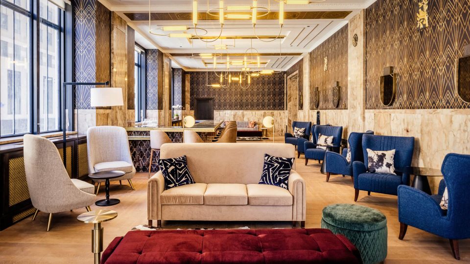 the lobby of a hotel with blue chairs and couches at The  First