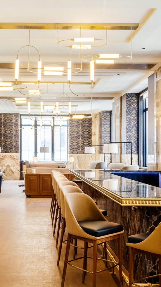 the lobby of a hotel with a long bar and chairs at The  First