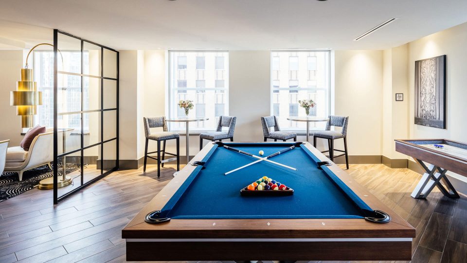 a pool table in a living room with chairs at The  First