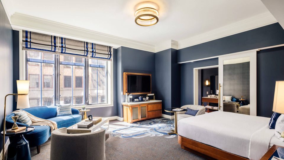 a hotel room with blue walls and a large bed at The  First