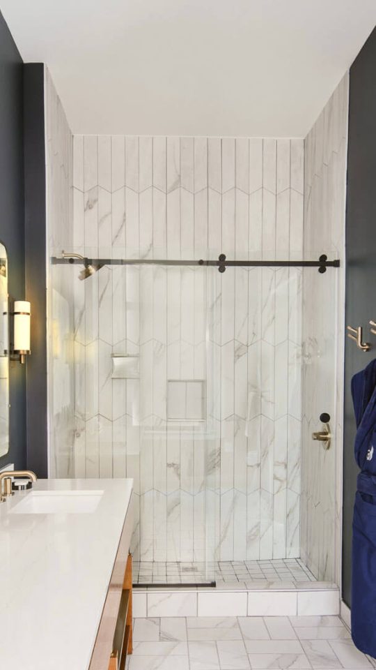 a bathroom with a marble counter top and a glass shower door at The  First