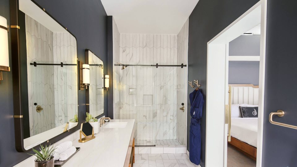 a bathroom with a marble counter top and a glass shower door at The  First