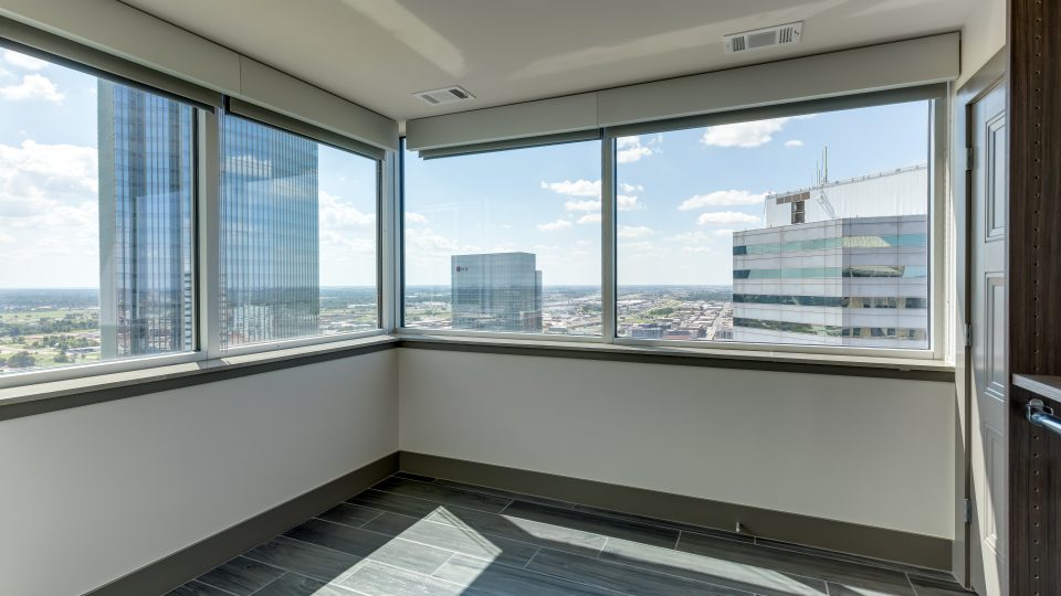 an empty room with large windows and a view of the city at The  First