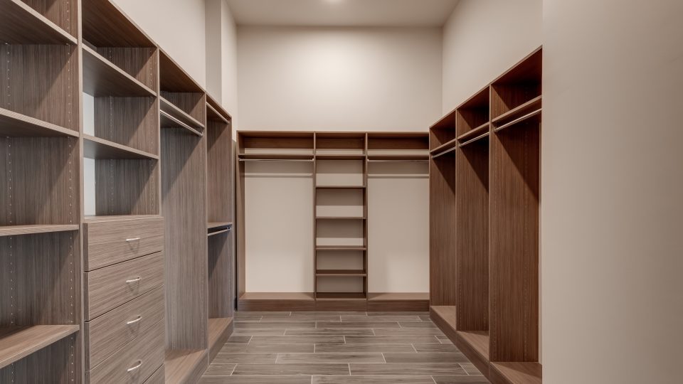 a walk in closet with shelves and cabinets at The  First