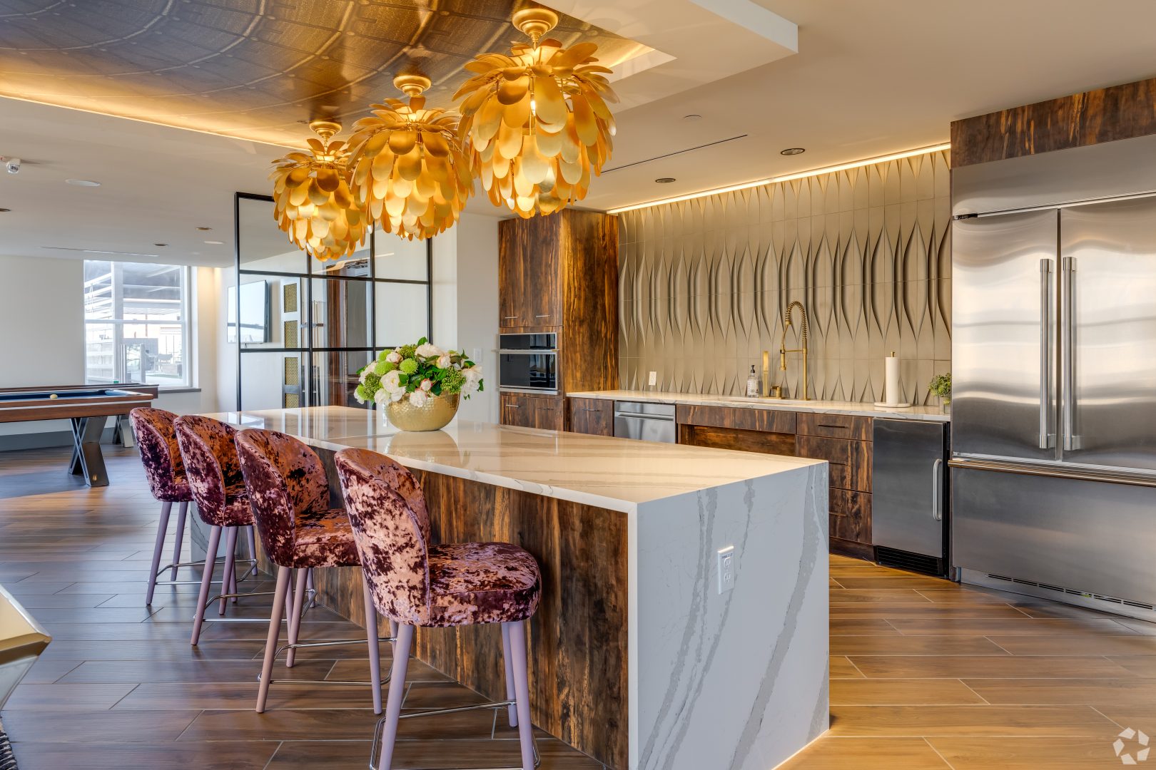 a kitchen with a marble island and gold pendant lights at The  First