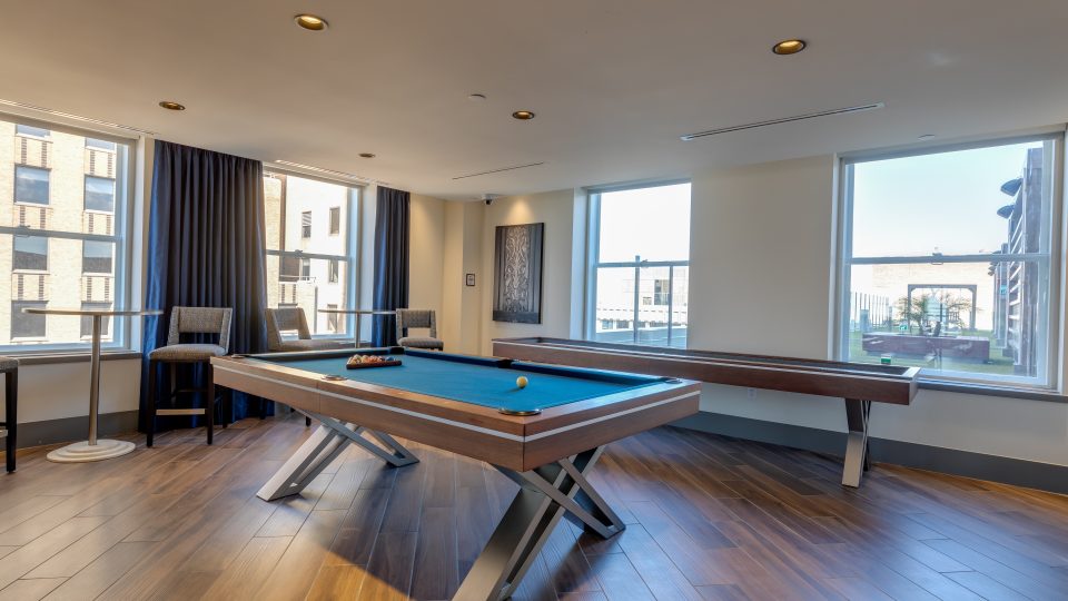 a pool table in a living room with windows at The  First