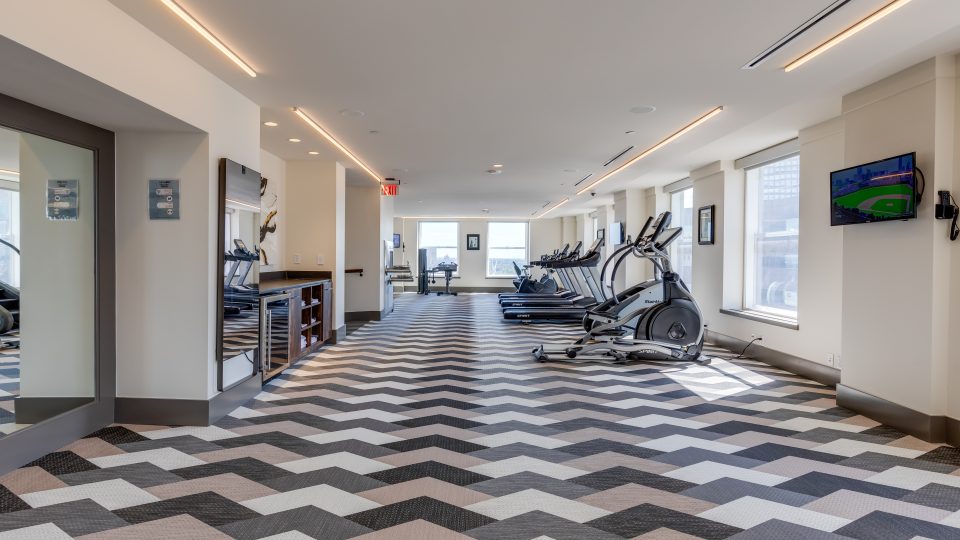 a gym room with treadmills and exercise equipment at The  First